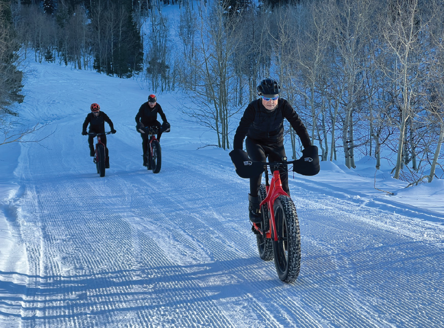 people fat biking up snowy road