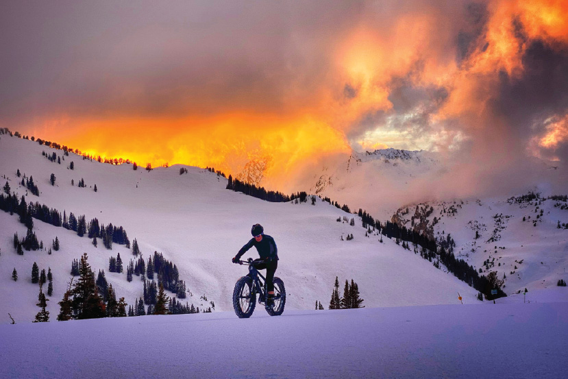 person fat biking with sunset