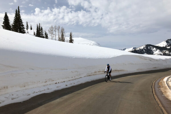 Person riding bike next to large snow pile